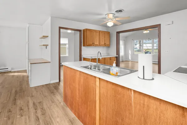 a dining hall with stainless steel appliances granite countertop a sink dishwasher and a dining table with wooden floor