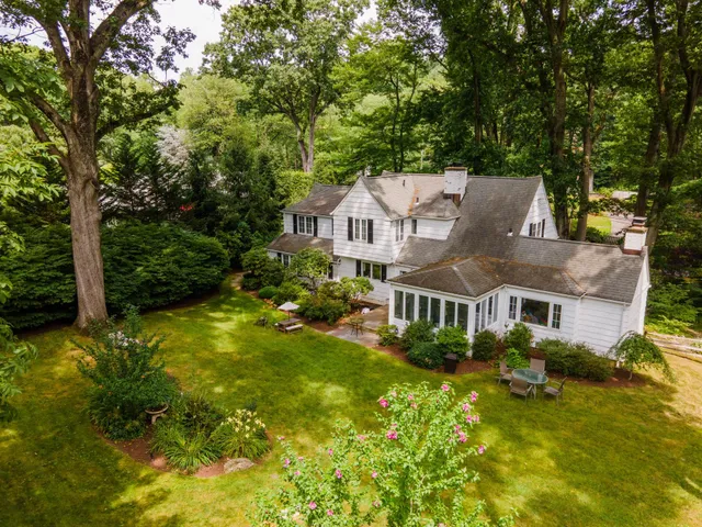 a view of a house with a big yard plants and large trees