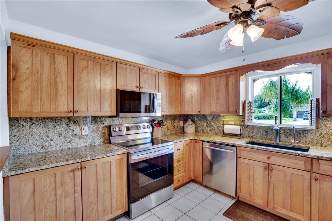 7666 134th Street Sebastian, FL 32958 - Photo 5 of 35 a kitchen with stainless steel appliances granite countertop a sink a stove cabinets and a kitchen island