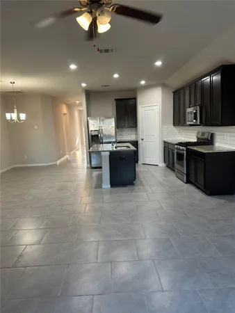 a large kitchen with a large counter top cabinets and stainless steel appliances