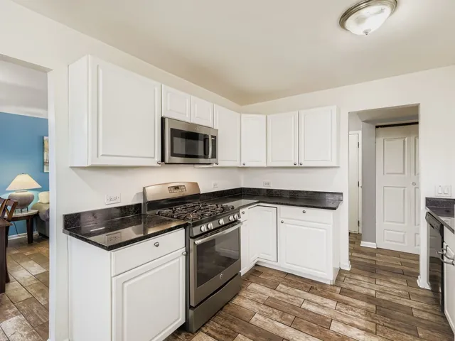 a kitchen with granite countertop white cabinets and appliances