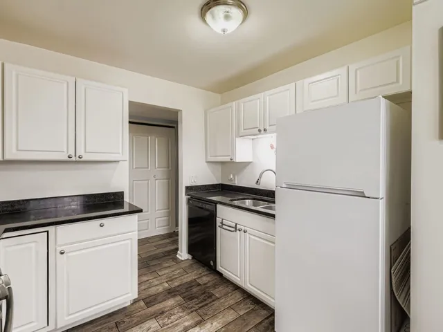 a kitchen with granite countertop white cabinets and white appliances