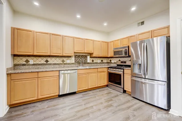 a kitchen with granite countertop white cabinets and stainless steel appliances