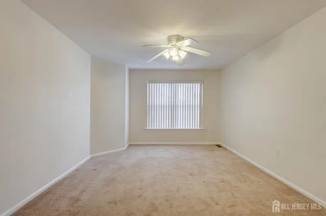 an empty room with a ceiling fan and window