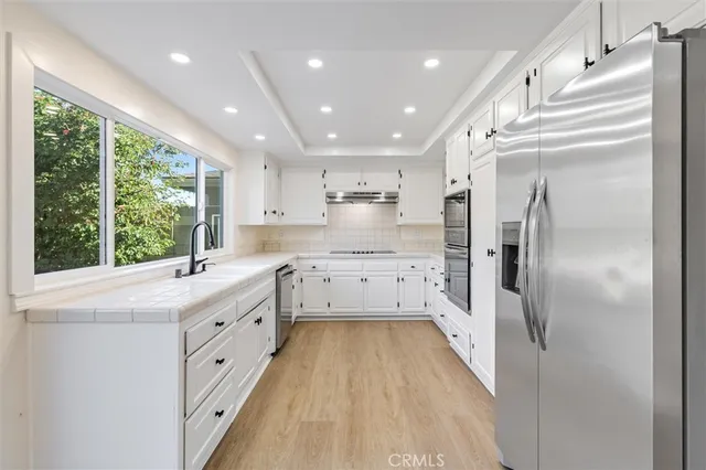 a kitchen with white cabinets and wooden floor