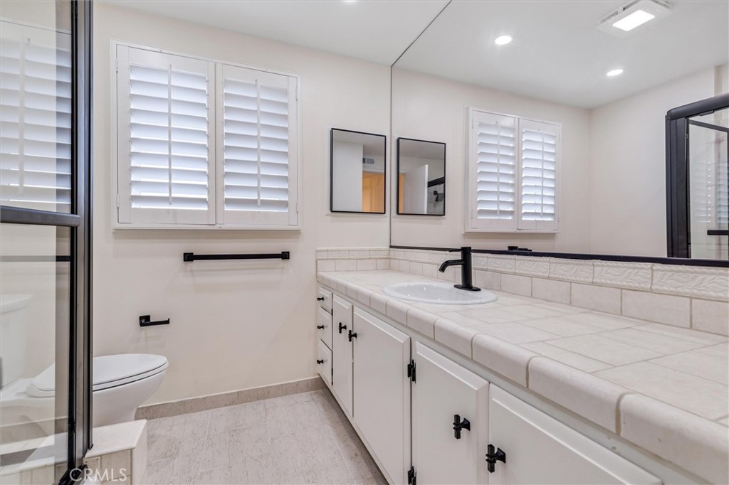 4533 Ironwood Avenue Seal Beach, CA 90740 - Photo 20 of 24 a bathroom with a granite countertop sink a toilet and a large mirror
