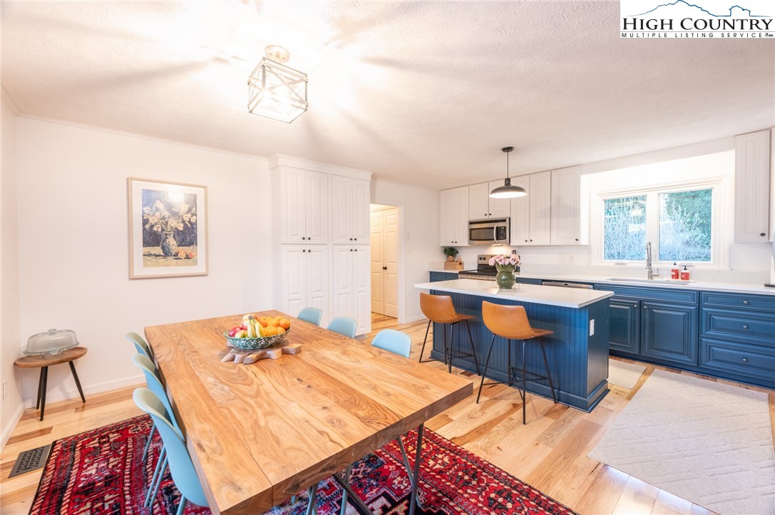 197 Sierra Vista Boone, NC 28607 - Photo 14 of 41 a kitchen with stainless steel appliances kitchen island granite countertop a refrigerator a sink dishwasher a dining table and chairs with wooden floor