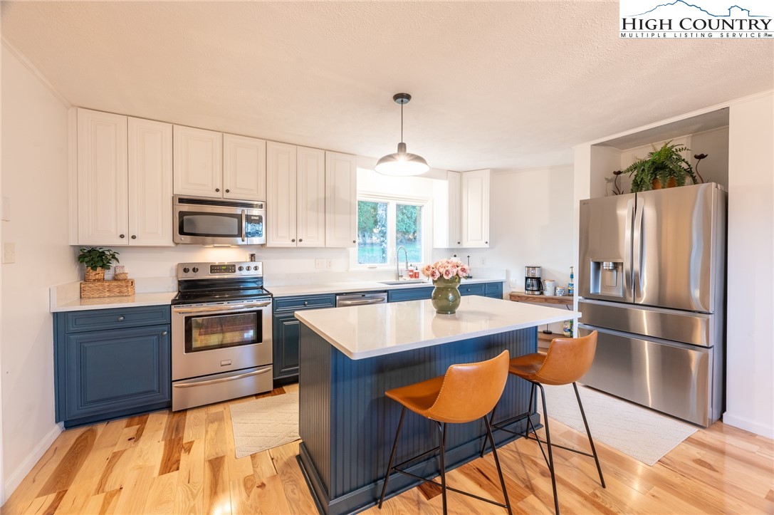 197 Sierra Vista Boone, NC 28607 - Photo 15 of 41 a kitchen with stainless steel appliances granite countertop a stove a refrigerator a sink a dining table and chairs with wooden floor