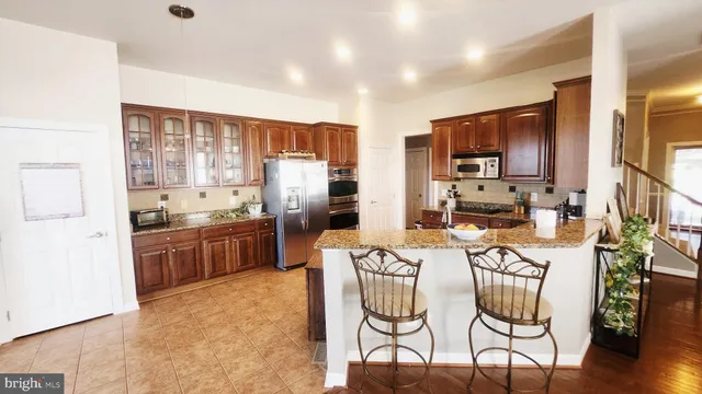 a kitchen with stainless steel appliances kitchen island granite countertop a refrigerator a stove a sink a oven with a dining table and chairs