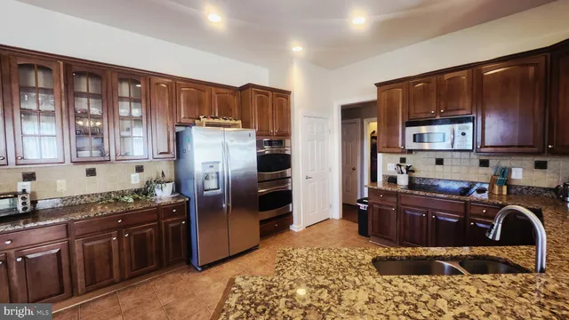 a kitchen with stainless steel appliances granite countertop a refrigerator stove top oven and granite countertops