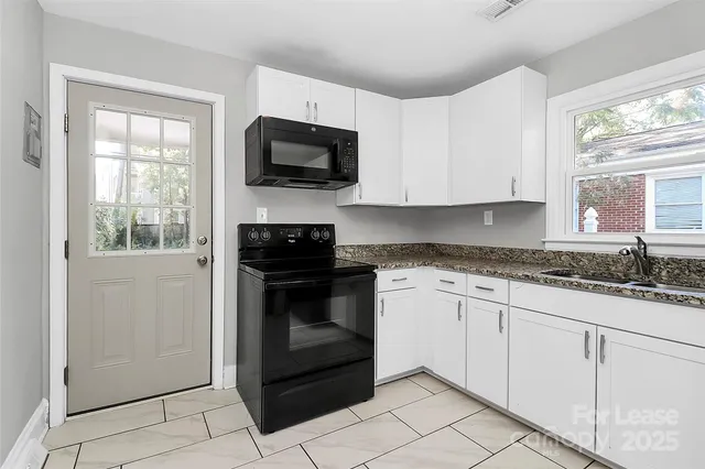 a kitchen with granite countertop white cabinets stainless steel appliances and window