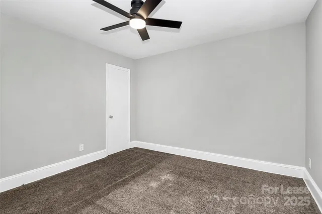 an empty room with a ceiling fan and carpet
