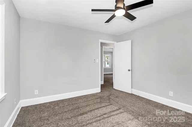 an empty room with a ceiling fan and carpet