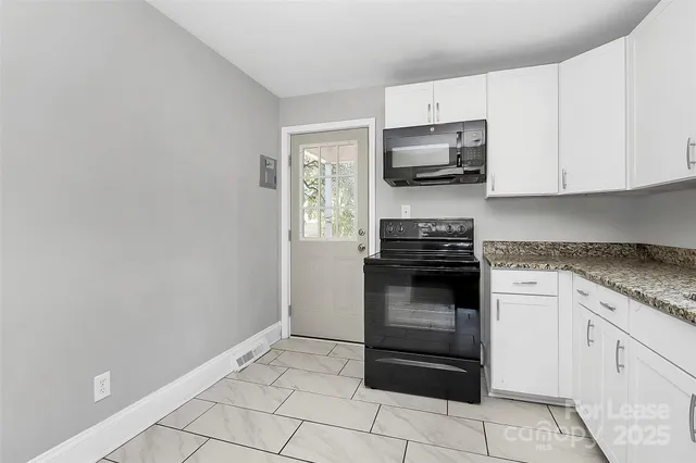 a kitchen with granite countertop white cabinets and stainless steel appliances