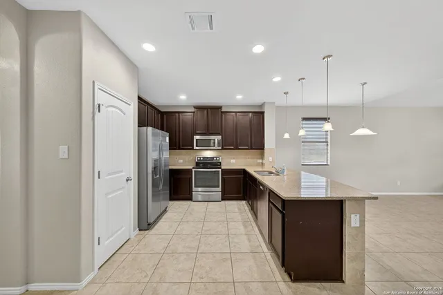 a large kitchen with a large counter top stainless steel appliances and cabinets