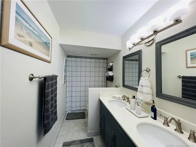 a bathroom with a double vanity sink a toilet a mirror and shower