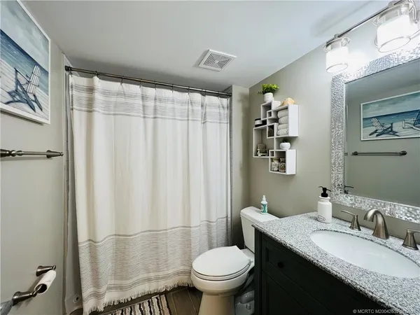 a bathroom with a granite countertop sink toilet and a mirror