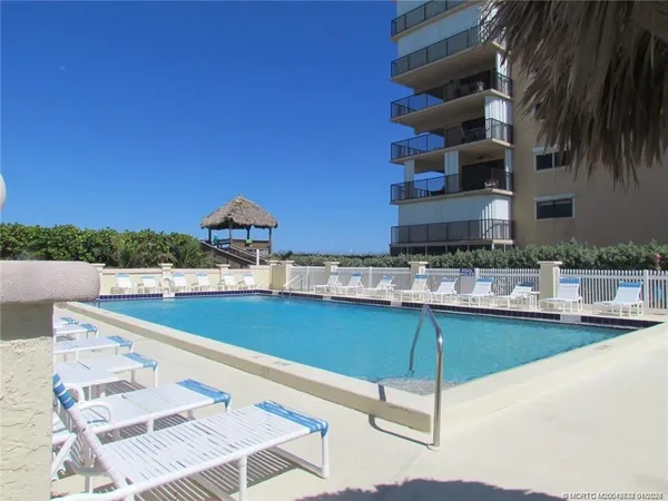 a view of a swimming pool with outdoor seating and buildings in the background