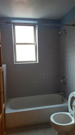 a bathroom with a bathtub a window and a shower