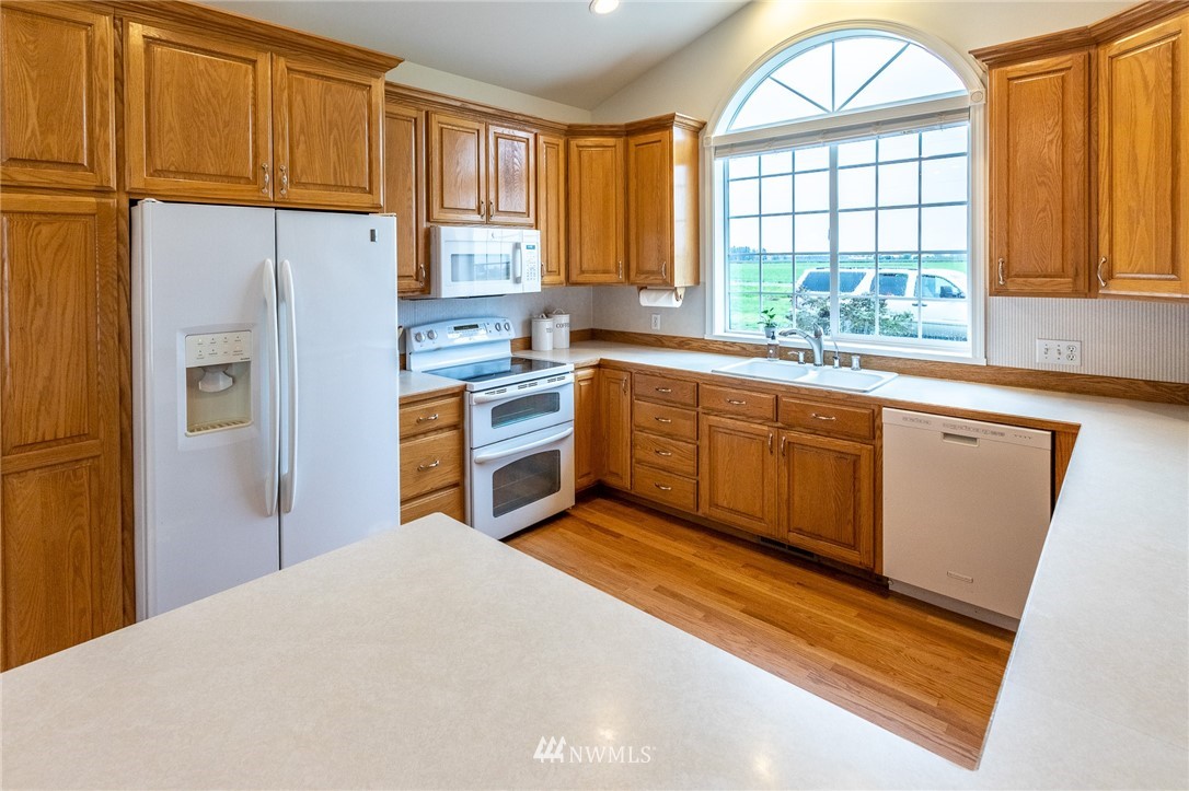 9147 Benson Road Lynden, WA 98264 - Photo 14 of 40 a kitchen with stainless steel appliances granite countertop a refrigerator a sink dishwasher and wooden cabinets with wooden floor
