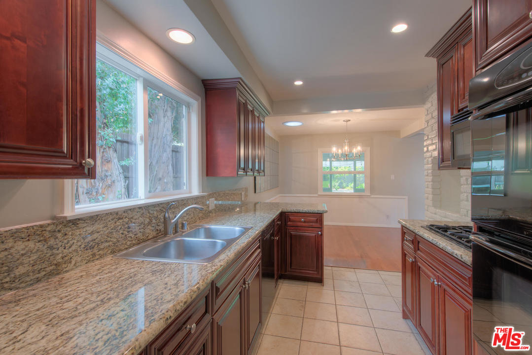 4739 Libbit Avenue Encino, CA 91436 - Photo 7 of 23 a kitchen with granite countertop a sink a counter top space cabinets and stainless steel appliances