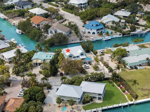 an aerial view of ocean and residential houses with outdoor space