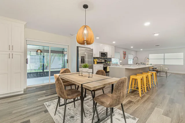 a kitchen with stainless steel appliances kitchen island granite countertop a table chairs and a wooden floor