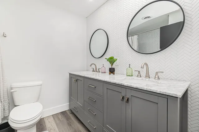 a bathroom with a granite countertop toilet a sink and a mirror