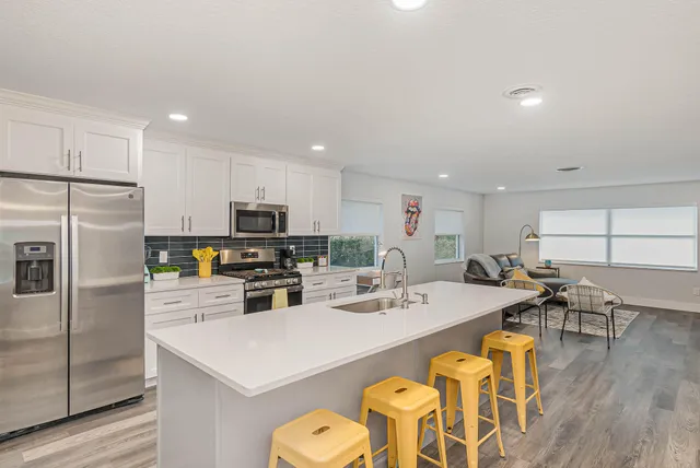 a kitchen with a sink a stove a refrigerator and white cabinets with wooden floor