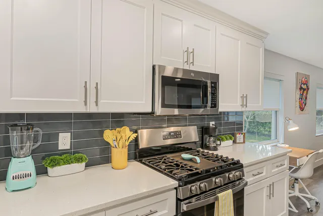 a kitchen with stainless steel appliances granite countertop a stove a microwave a sink and cabinets