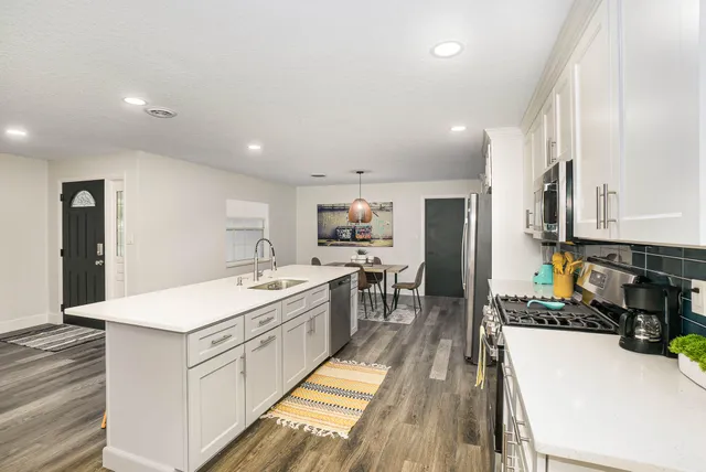 a large white kitchen with a large window and stainless steel appliances