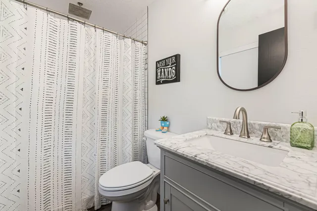 a bathroom with a granite countertop toilet sink and mirror