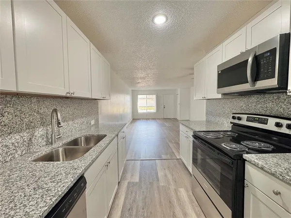 a kitchen with stainless steel appliances granite countertop a sink stove and microwave