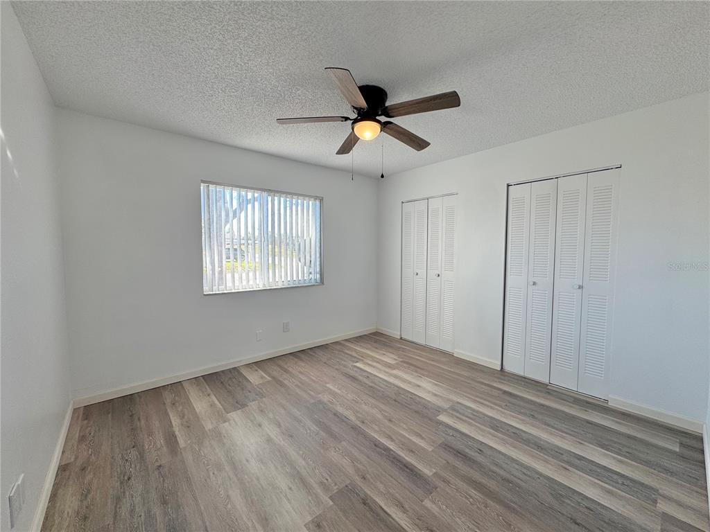 383 Winter Ridge Boulevard, Unit 383 Winter Haven, FL 33881 - Photo 20 of 35 an empty room with wooden floor ceiling fan and windows