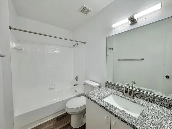 a bathroom with a granite countertop sink a toilet and shower