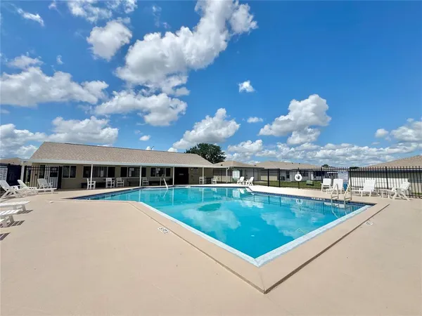 a view of back yard with swimming pool and seating in back