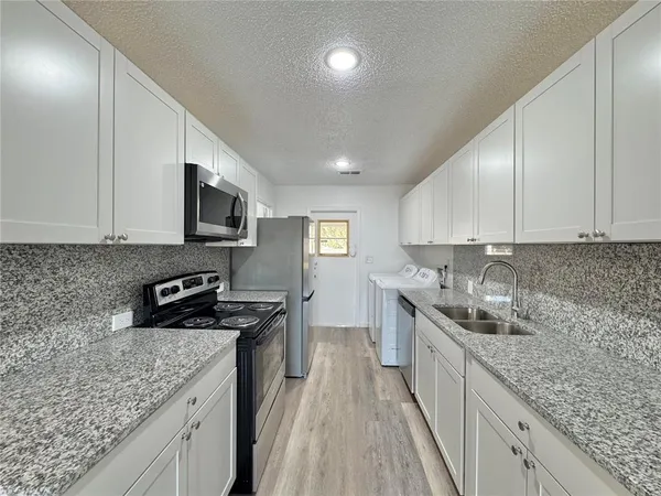 a kitchen with stainless steel appliances granite countertop a sink stove and refrigerator