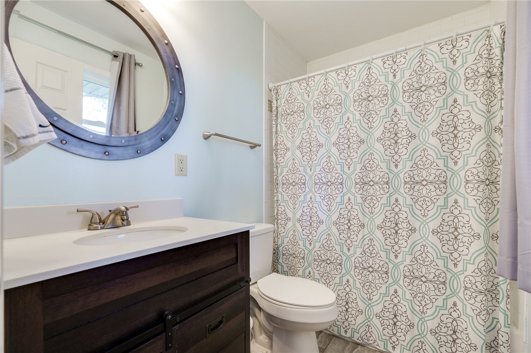 6950 Red Lion 5 Points Road Springboro, OH 45066 - Photo 31 of 78 This bright bathroom features a vanity, mirror, toilet, and shower with a decorative curtain.