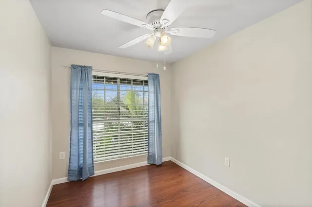 an empty room with wooden floor and fan