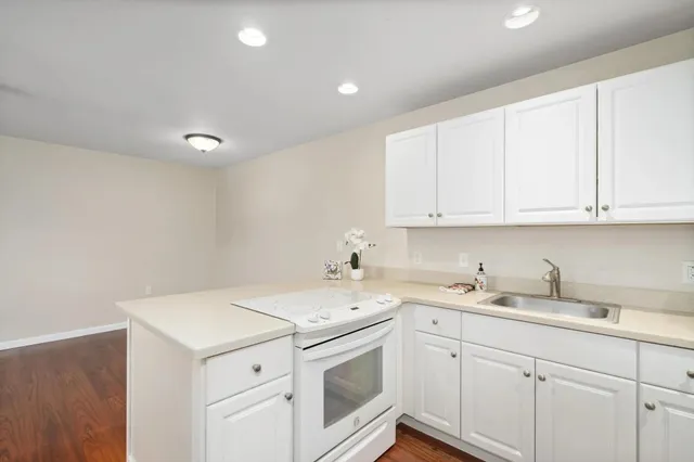 a kitchen with a sink a stove a refrigerator and white cabinets