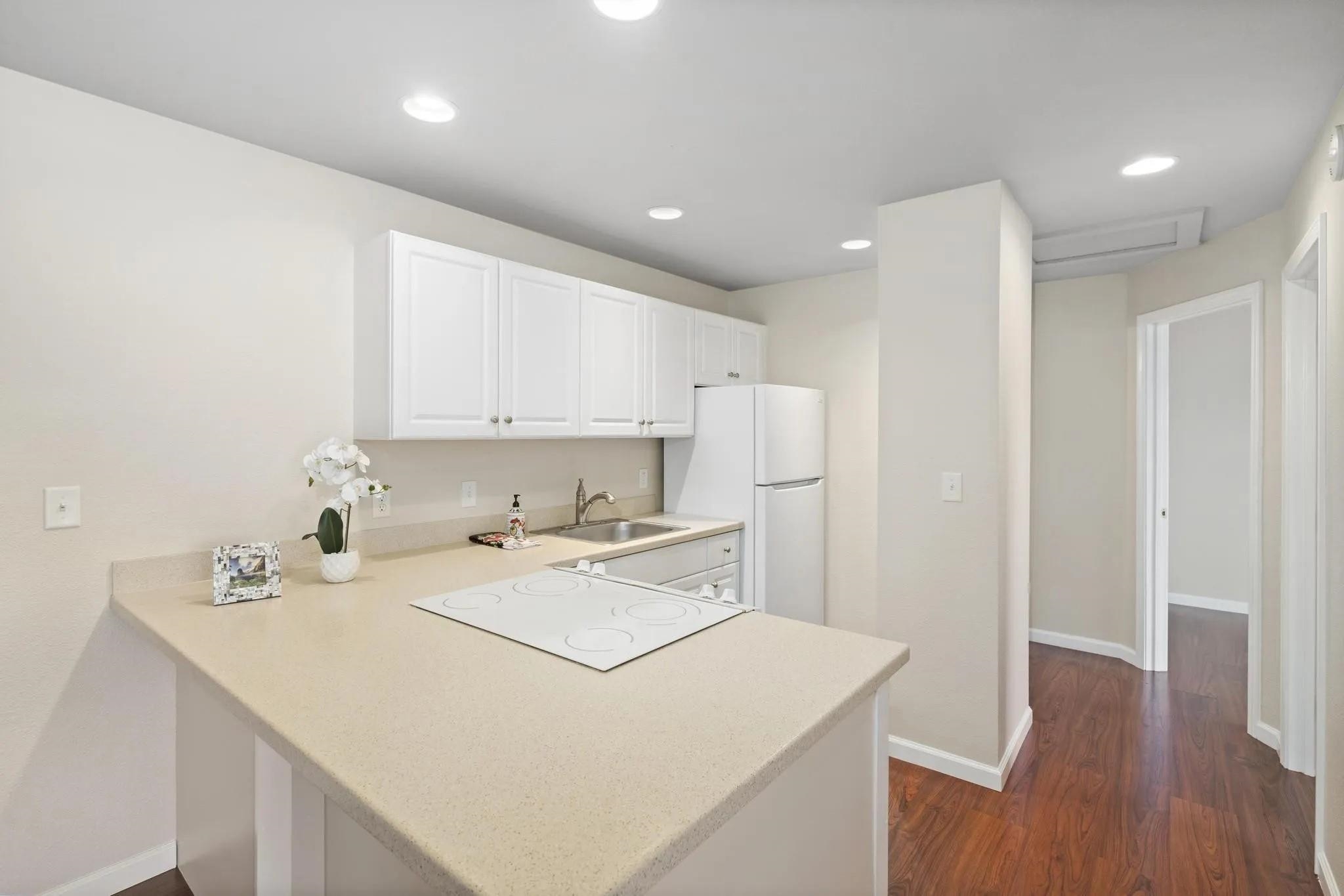 160 Keonekai Road, Unit 14202 Kihei, HI 96753 - Photo 9 of 21 a kitchen with a sink a stove a refrigerator and white cabinets