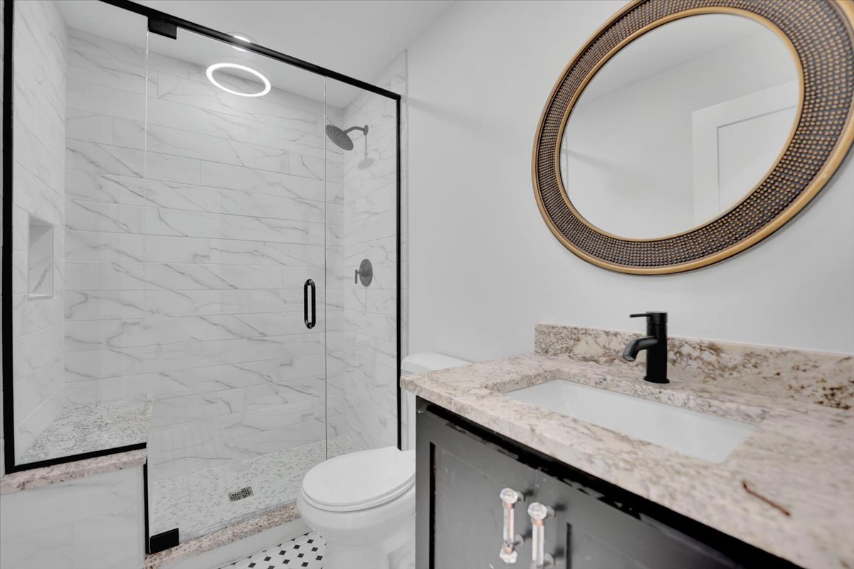 101 Devonshire Road, Unit 1 Tower Lakes, IL 60010 - Photo 16 of 38 a bathroom with a granite countertop sink a toilet mirror and shower
