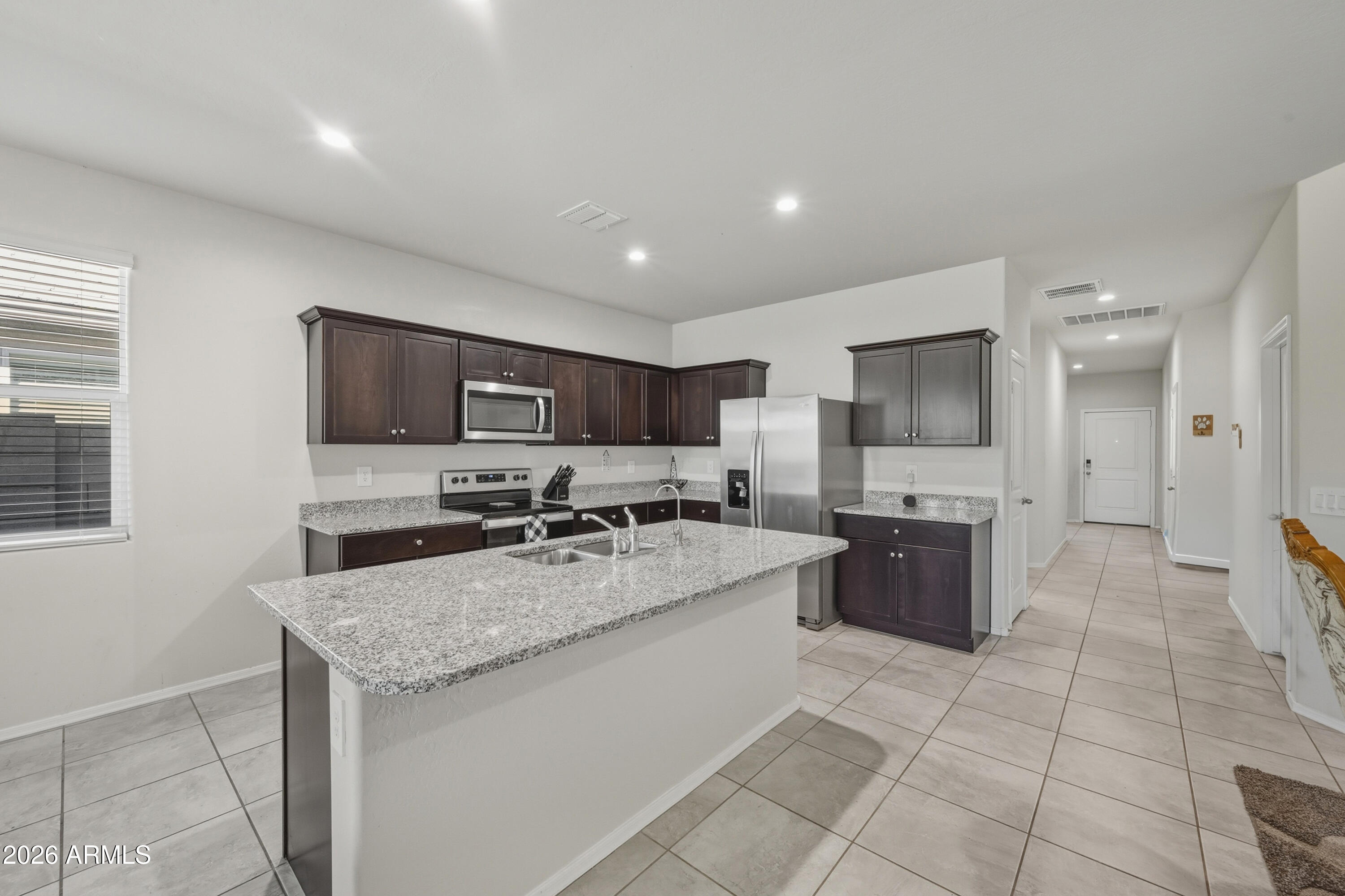 24136 Plow Road Florence, AZ 85132 - Photo 8 of 23 a large kitchen with kitchen island granite countertop a stove a sink a microwave and a refrigerator