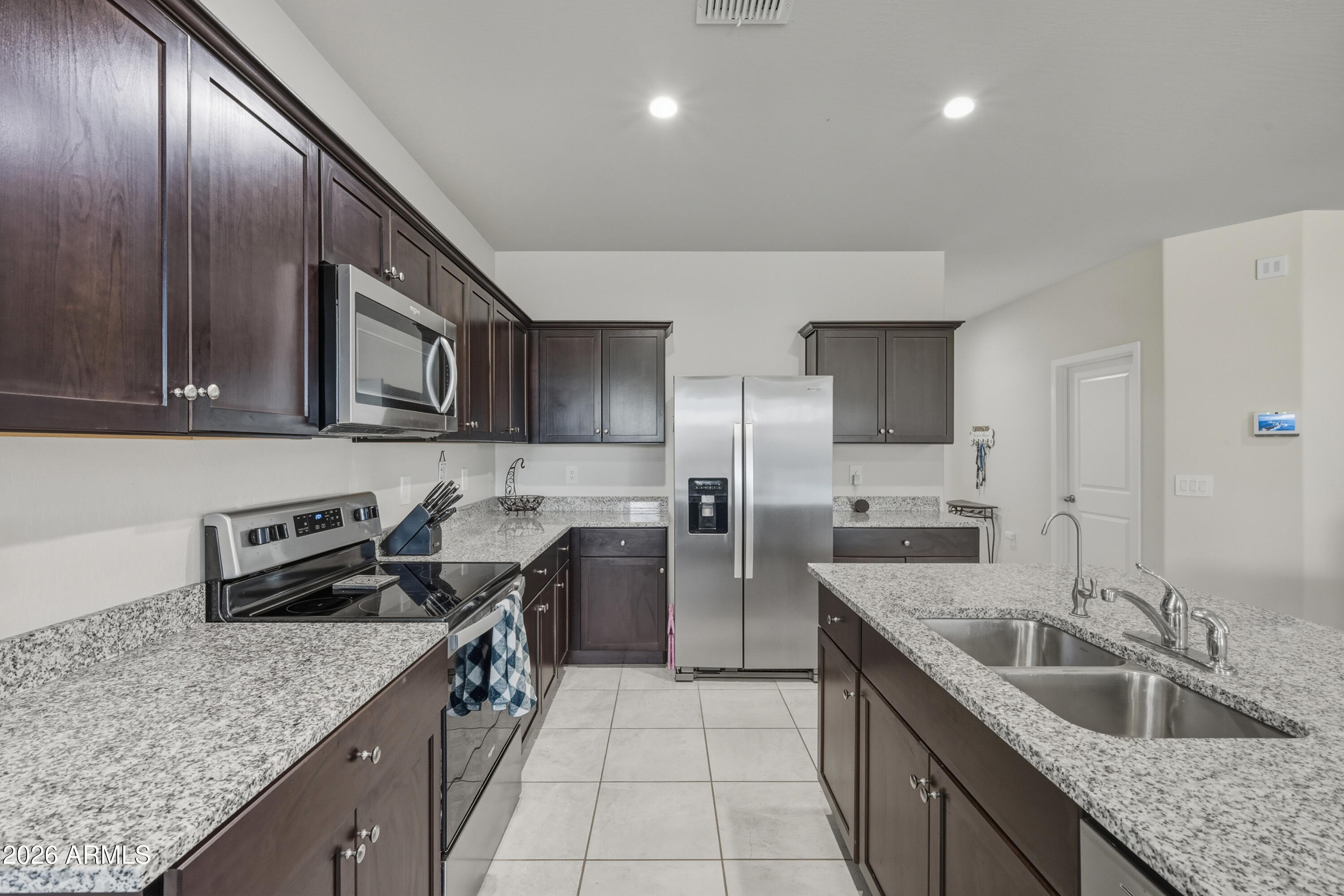 24136 Plow Road Florence, AZ 85132 - Photo 9 of 23 a kitchen with stainless steel appliances granite countertop a sink a stove and a wooden cabinets