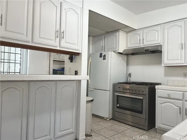 a kitchen with stainless steel appliances granite countertop white cabinets and a stove top oven