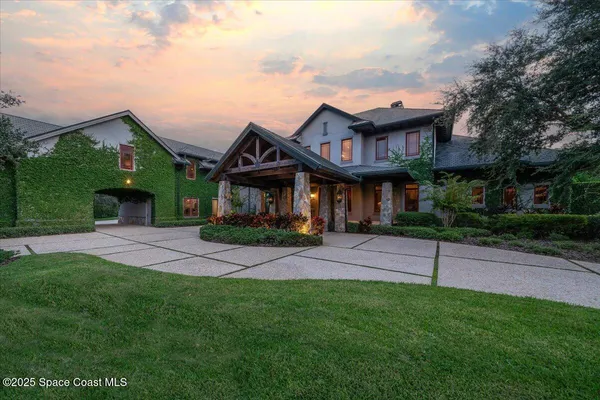 a view of a white house with a big yard and potted plants