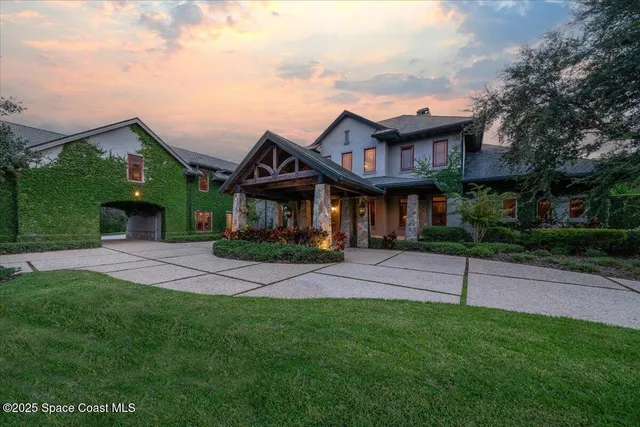 a view of a white house with a big yard and potted plants