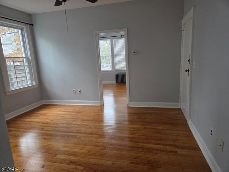 292 Leslie Street, Unit 1R Newark, NJ 07112 - Photo 2 of 9 an empty room with wooden floor and windows