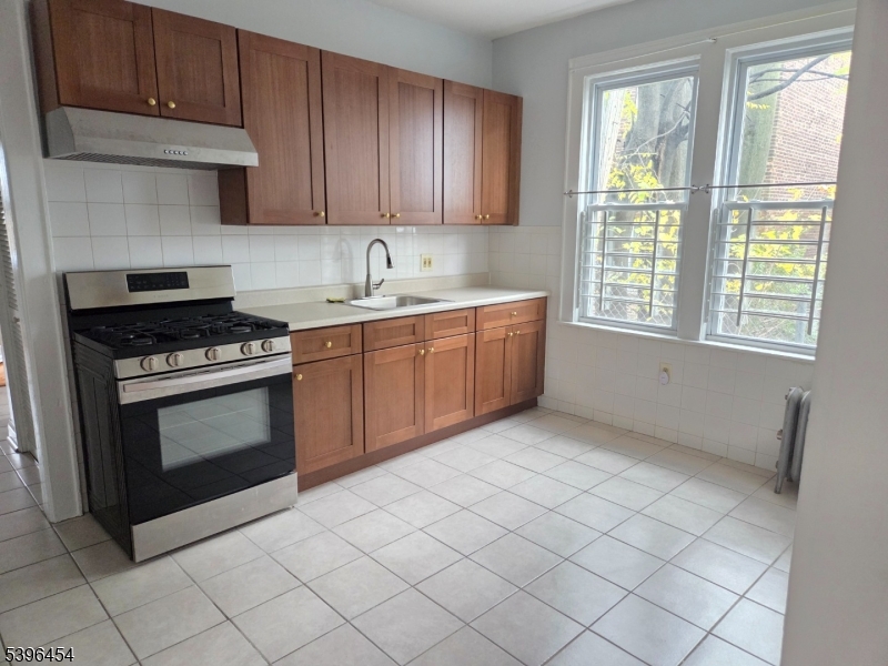 292 Leslie Street, Unit 1R Newark, NJ 07112 - Photo 6 of 9 a kitchen with granite countertop a stove sink and cabinets