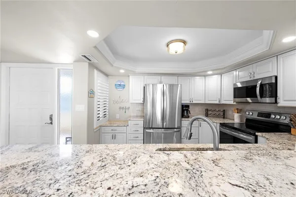 a kitchen with stainless steel appliances kitchen island granite countertop a refrigerator and a sink